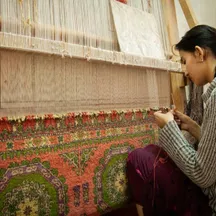 A weaver working at a carpet loom